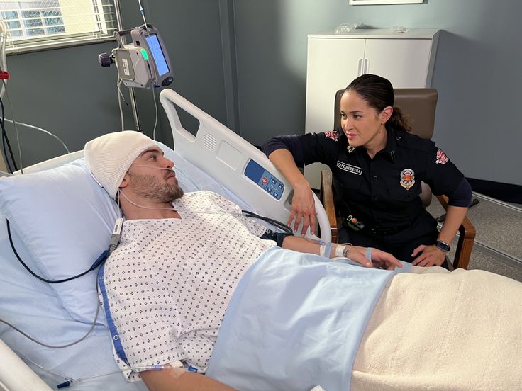 a man laying in a hospital bed next to a woman who is holding an iv