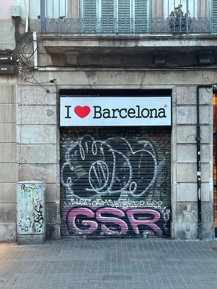 an old building with graffiti on the front and side doors that say i love barcelona