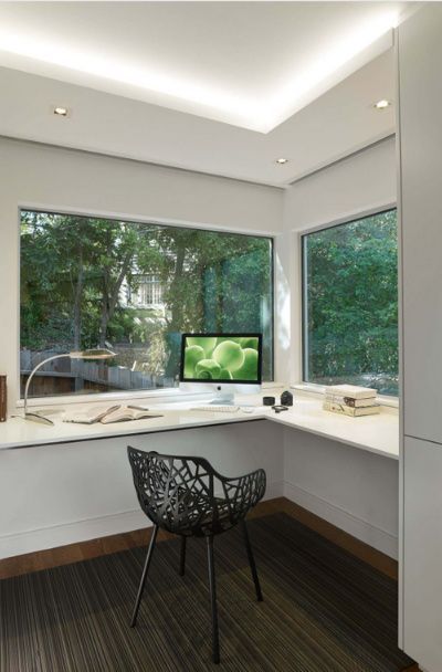 a room with a desk, chair and computer monitor in it's corner area