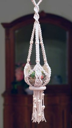 a white beaded hanging planter with flowers in it