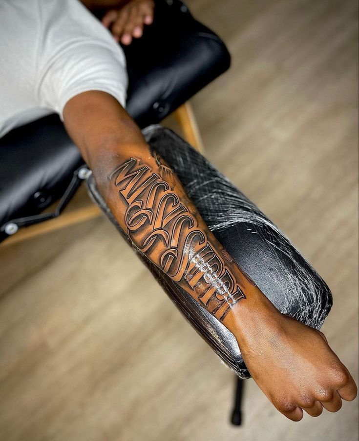 a man with a tattoo on his arm sitting in a chair