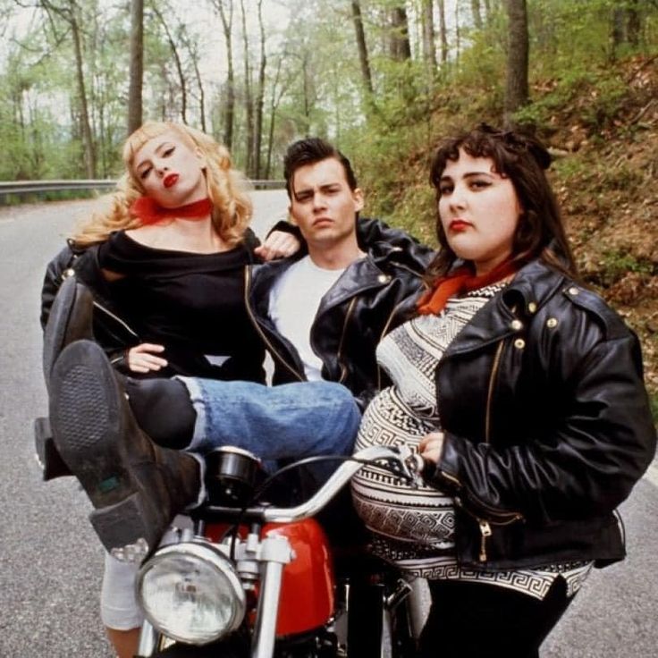 three people sitting on a motorcycle in the road