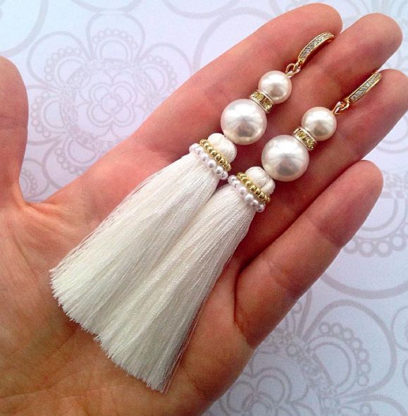 three tasseled pearls and white beads on a hand