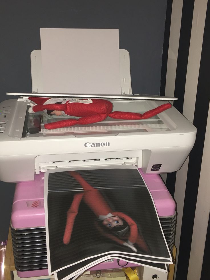 a canon printer sitting on top of a table next to a pink and white machine