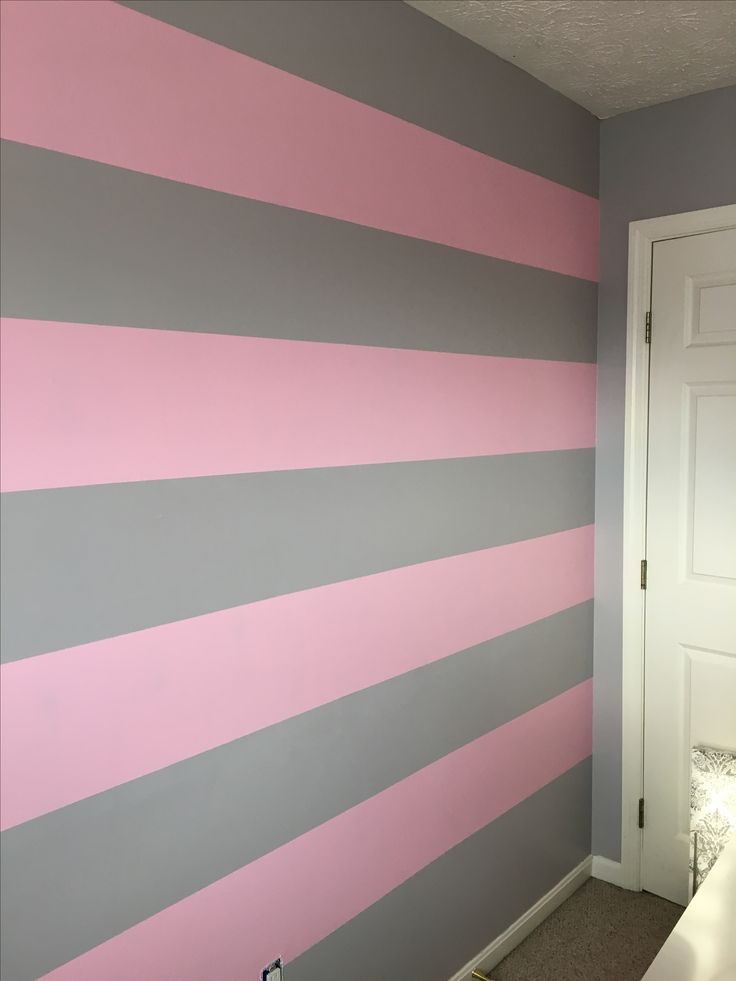 a room with pink, grey and white stripes painted on the wall next to a door