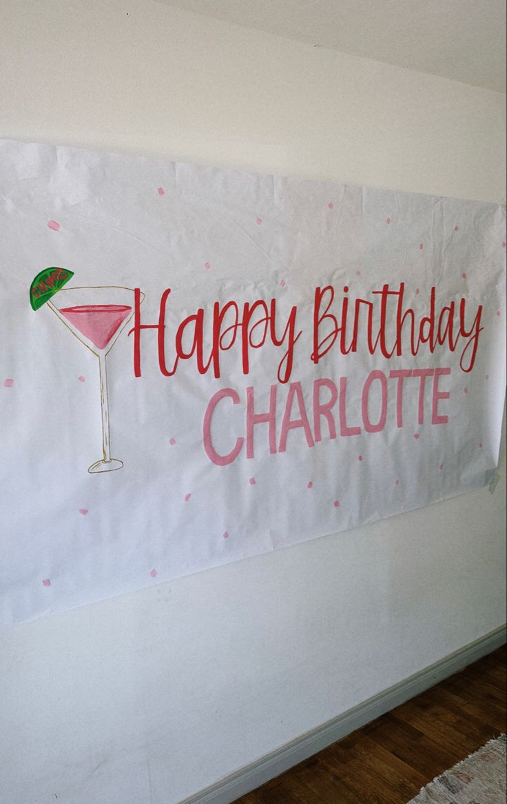 a happy birthday banner hanging on the wall with a martini glass in front of it