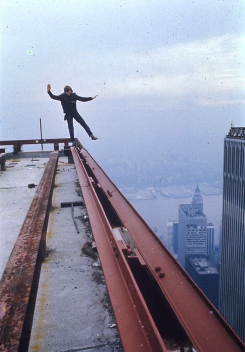 a man standing on the edge of a high building with his arms wide open and hands in the air