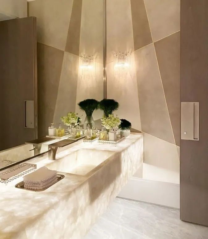 a bathroom with two sinks, mirrors and lights on the wall above them is decorated in shades of beige