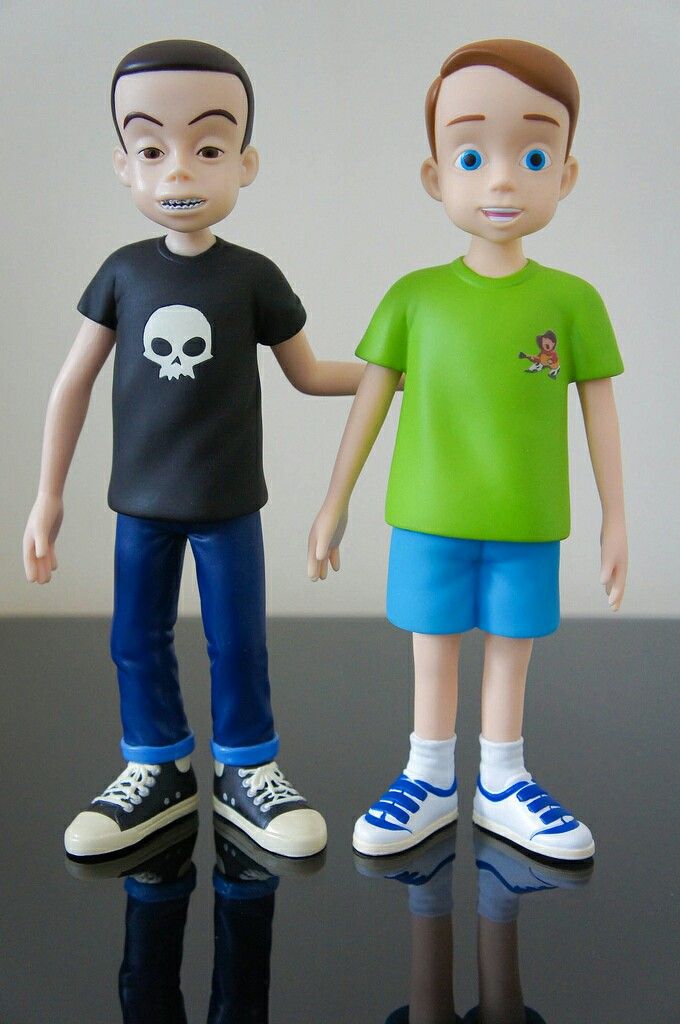 two toy figures standing next to each other on a black table with white walls behind them