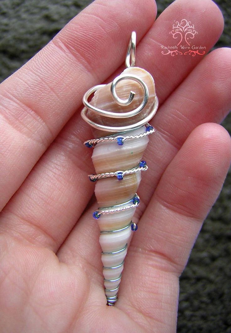 a person is holding a small pendant in their hand and it has a spiral design on it