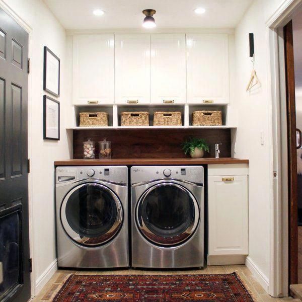 a washer and dryer in a small room with white cabinets, rugs and pictures on the wall