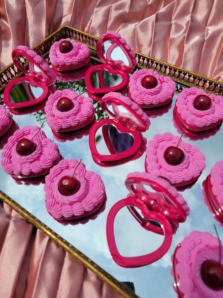 pink cupcakes are arranged in the shape of heart shapes on a mirror tray