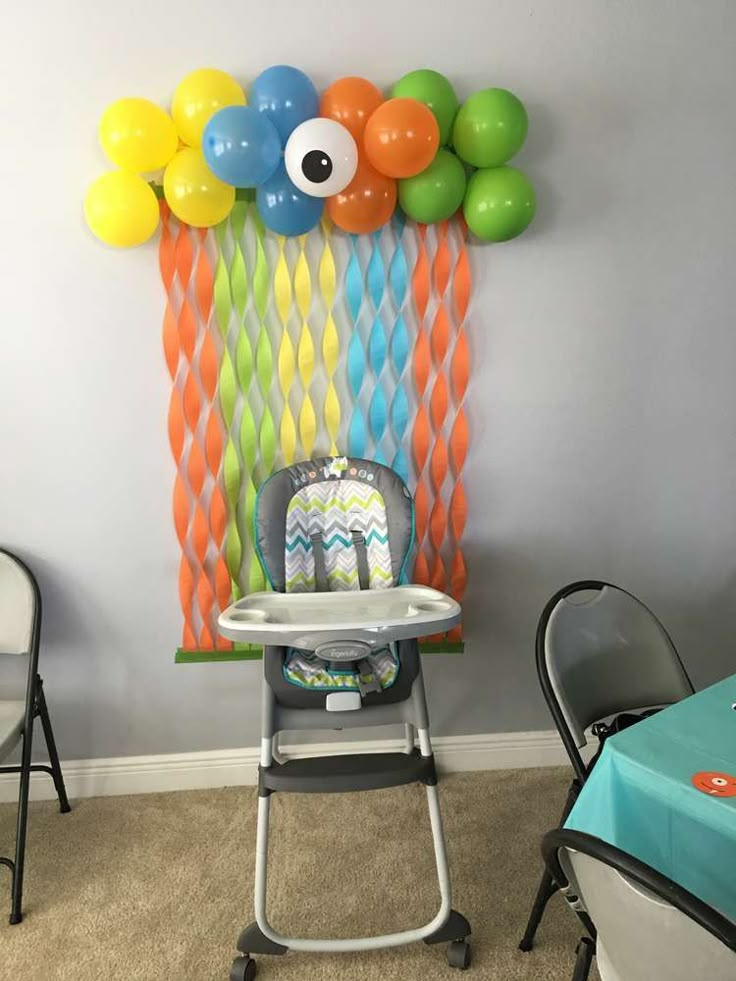 a baby's high chair with balloons hanging on the wall