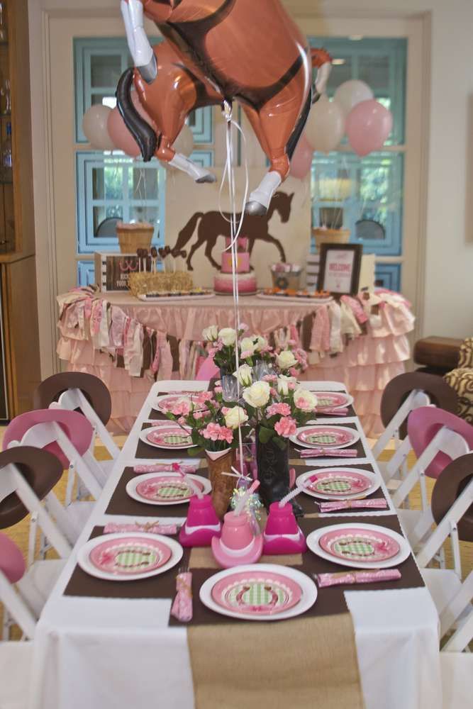 a table set up for a birthday party with pink and brown plates, balloons and decorations