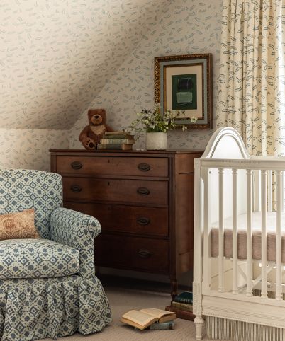 a baby's room with a chair, dresser and crib in it is shown