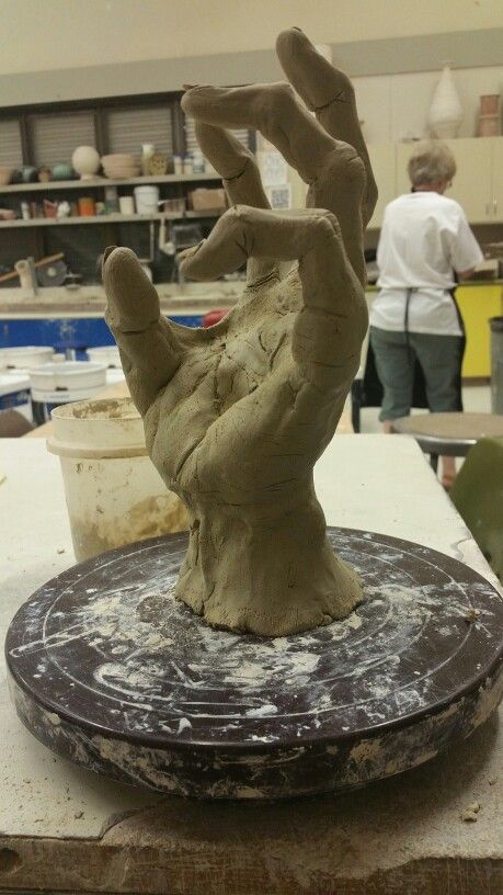 a clay hand sitting on top of a piece of pottery