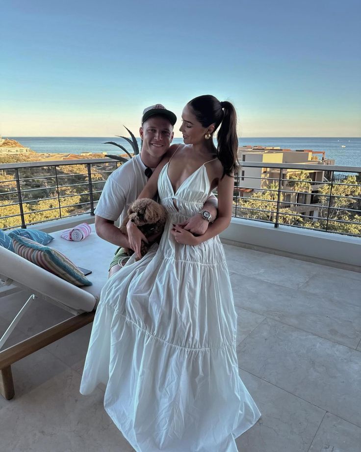 a man and woman standing on a balcony next to each other holding teddy bears in their hands