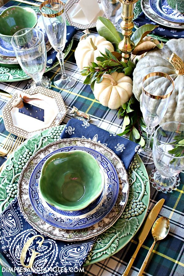 the table is set with blue and green plates, silverware, and pumpkins