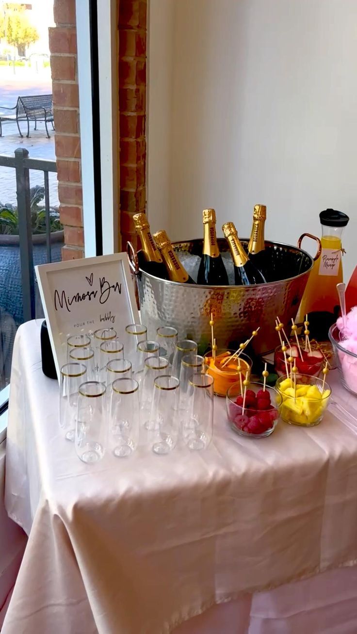 a table topped with lots of bottles of wine and glasses filled with fruit on top of it