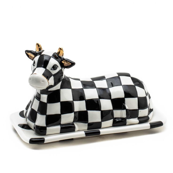 a black and white cow figurine sitting on top of a plate