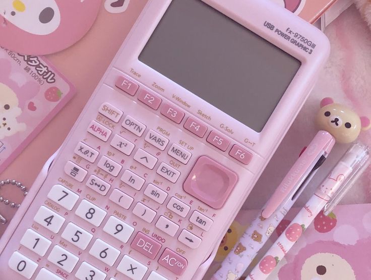 a pink calculator sitting on top of a table next to a pen and paper