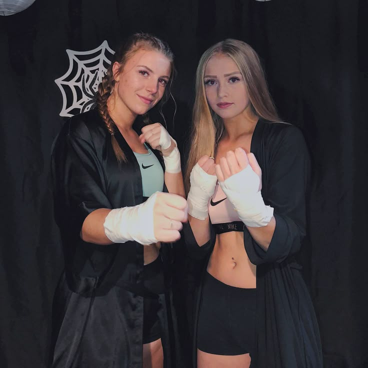 two beautiful young women standing next to each other wearing boxing gloves and holding white gloves