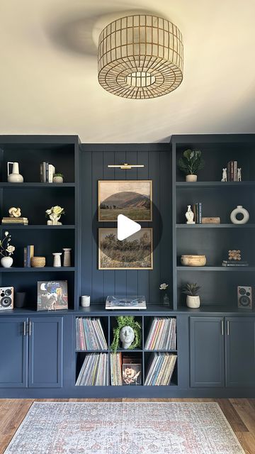 a living room with blue bookcases and a white rug on the hardwood floor