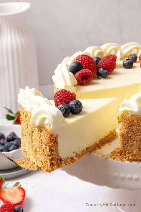 a cheesecake with berries and cream on top sits on a plate, ready to be eaten