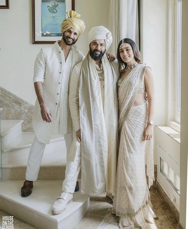 three people standing next to each other in front of a window wearing white outfits and turbans