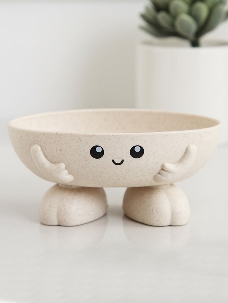 a white bowl sitting on top of a table next to a potted plant