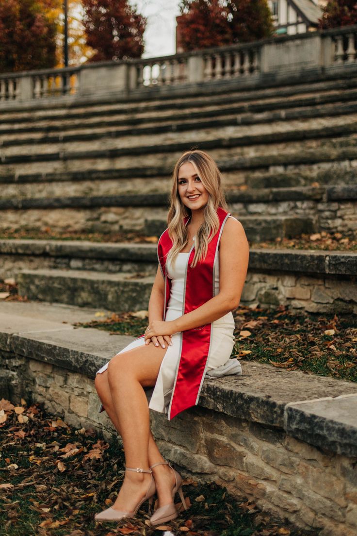 a woman sitting on steps in front of some stairs with her legs crossed and smiling at the camera