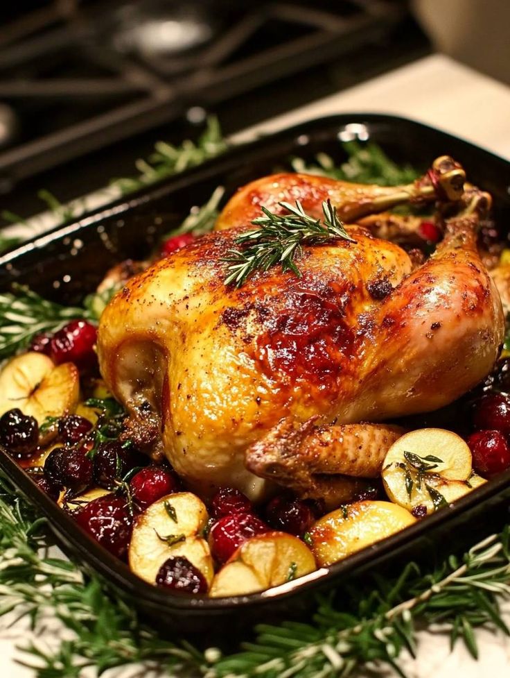 a roasted turkey with cranberries and potatoes in a roasting pan on a counter