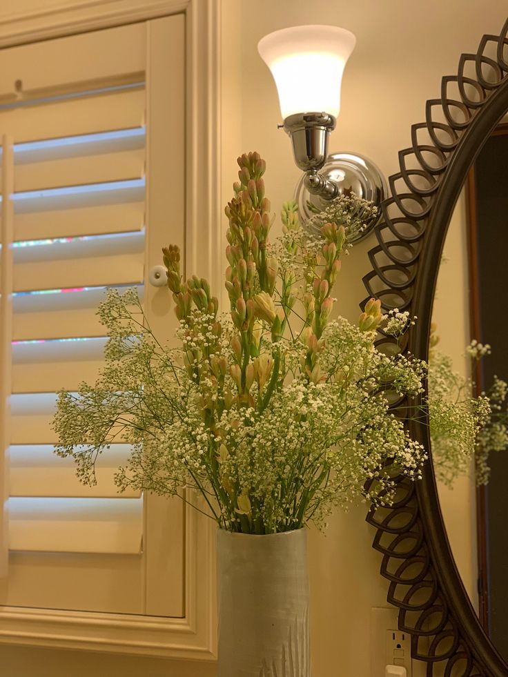 a vase filled with flowers next to a mirror