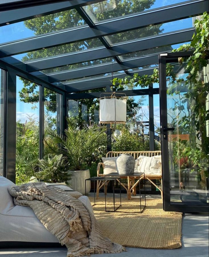 a living room filled with furniture and lots of plants on top of a wooden floor