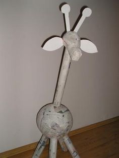 a metal giraffe sculpture sitting on top of a wooden floor next to a wall