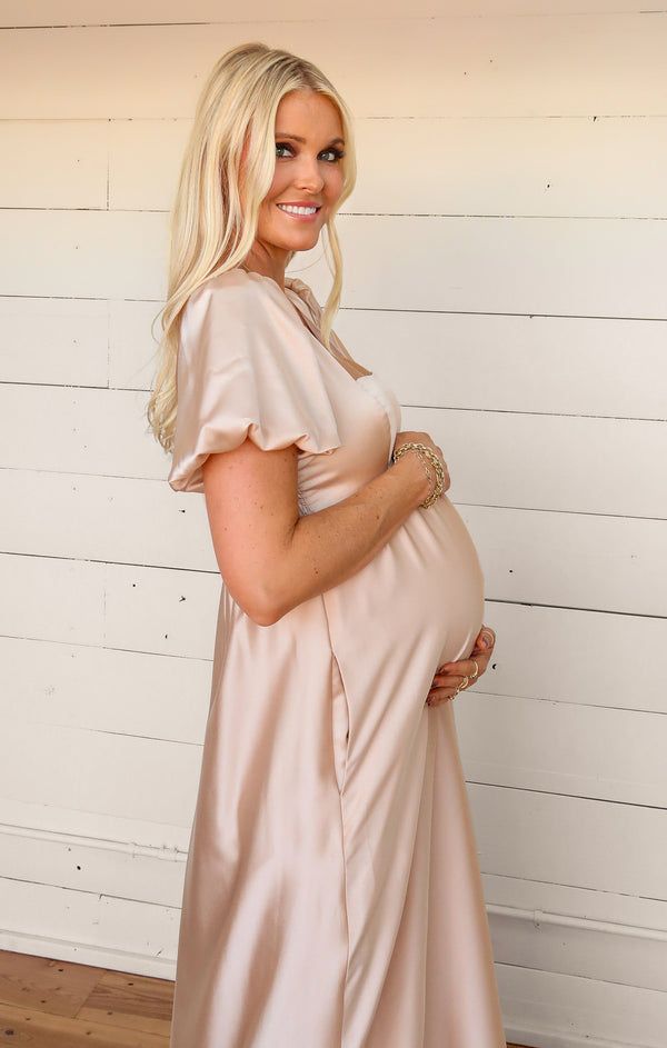 a pregnant woman in a dress poses for the camera with her hands on her belly