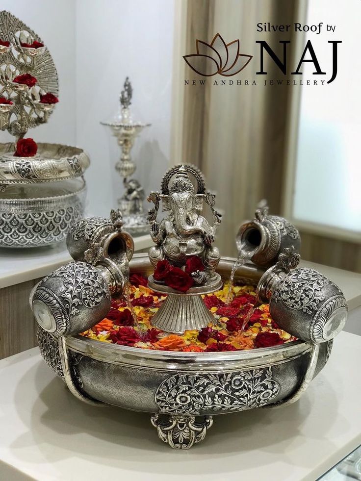 an ornate silver plate with red and yellow flowers in it on top of a table