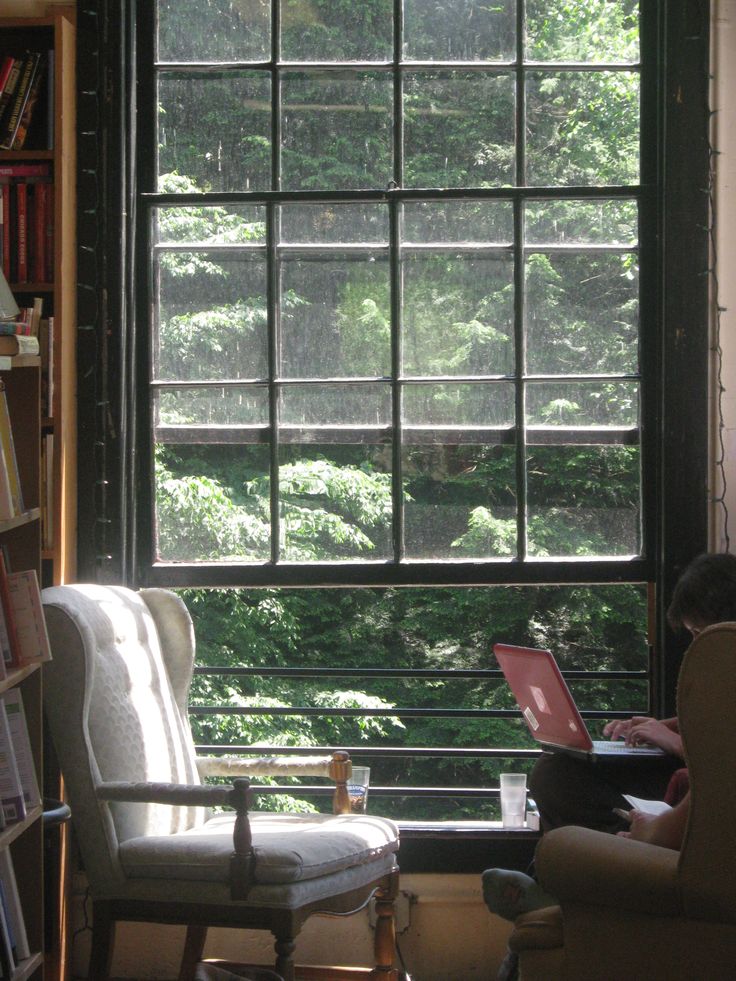 a person sitting on a chair in front of a window with an open laptop computer