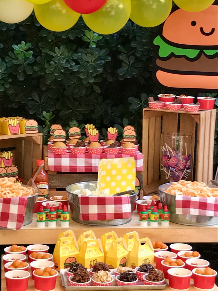 a table topped with lots of food next to a bunch of balloons and buns