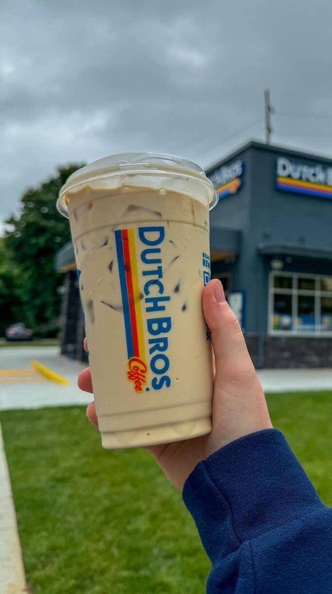 a person holding up a cup of dunkin'donuts