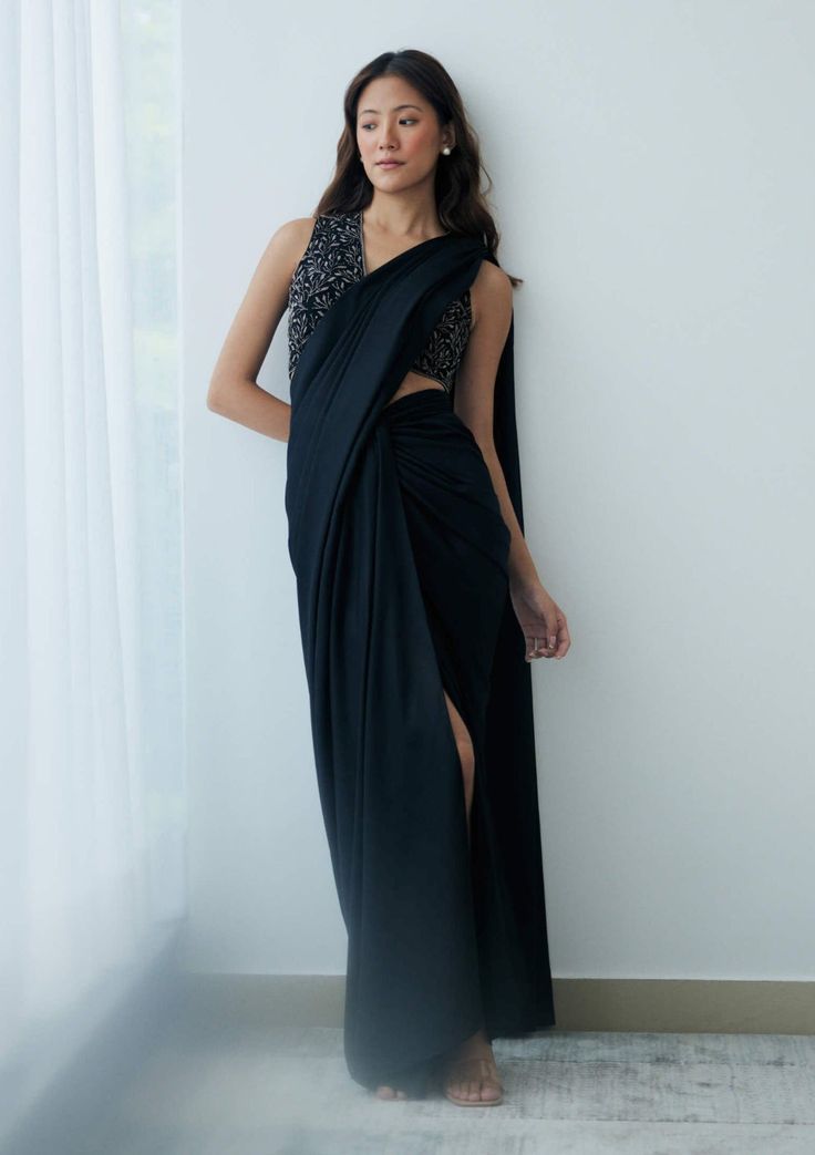 Elevate your evening look effortlessly with this pre-stitched sari. It features a knot-drape skirt in shimmery black georgette with an attached drape and a sleeveless beaded blouse boasting a plunging v-neckline. This ensemble is lightweight and effortlessly chic, making a striking statement perfect for cocktail parties or evening festivities under the stars. Embellished Black Pre-draped Saree For Party, Elegant Black Silk Pre-draped Saree, Black Sequined Pre-draped Saree, Glamorous Black Pre-draped Saree, Black Pre-draped Saree With Sequins, Evening Party Wear Pre-draped Floor-length Saree, Elegant Black Embellished Pre-draped Saree, Elegant Black Pre-draped Saree With Sequins, Elegant Black Pre-draped Saree For Evening