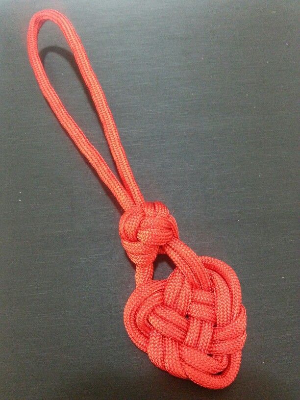 an orange knot on a black surface with a piece of string in the middle that is attached to it