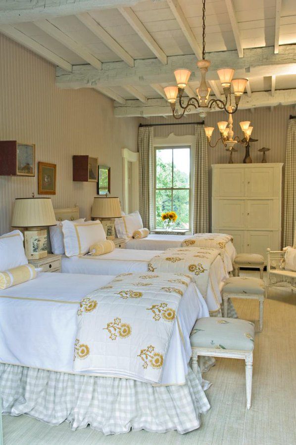 three beds in a room with white walls and wooden beams, two lamps on either side of the bed