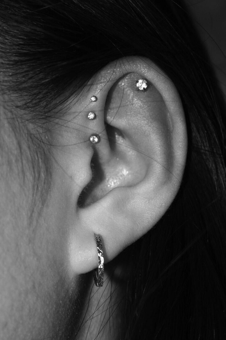 a woman's ear with three piercings on it