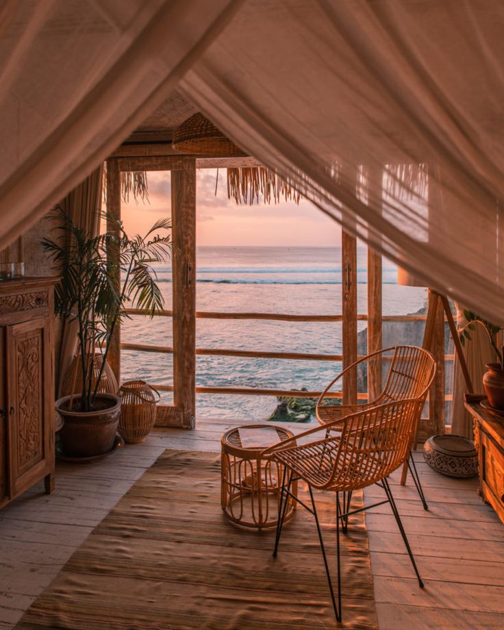 a room with a bed, table and chairs on the floor next to an ocean view