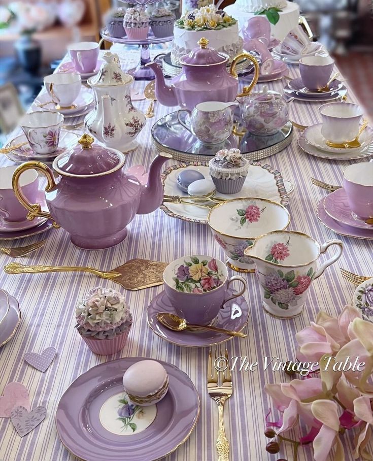 a table topped with lots of purple tea cups and saucers