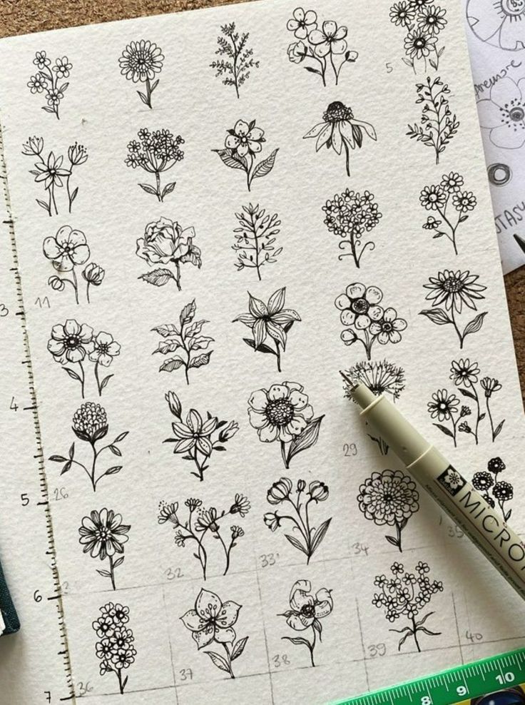 some flowers are drawn on top of a piece of paper next to a ruler and markers