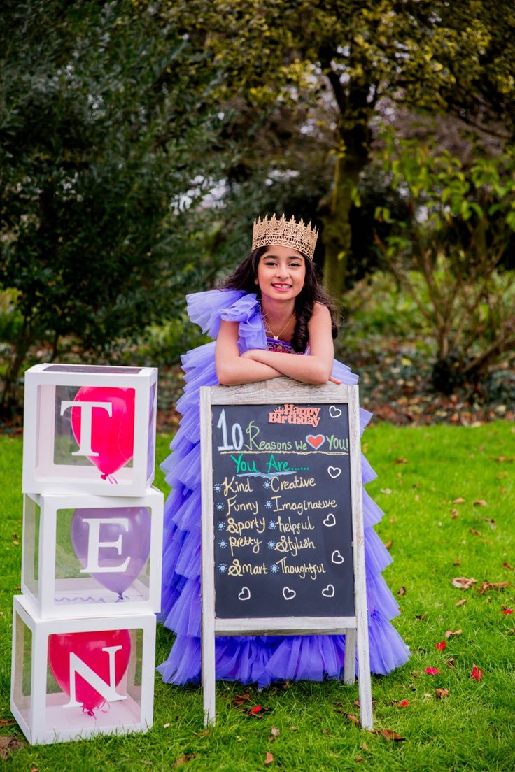 a woman in a purple dress standing next to a sign