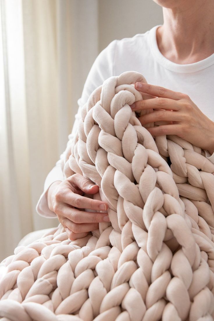 a man is holding a giant chunky blanket