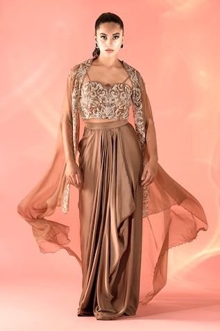 Copper metallic cape with floral pattern dori embroidery. Comes with coordinating embroidered padded bustier and a draped dhoti skirt. - Aza Fashions Traditional Embroidered Pre-draped Saree With Cape Sleeves, Embroidered Draped Dupatta For Party, Embroidered Draped Choli For Wedding, Fitted Dress With Cape Sleeves For Navratri, Wedding Embroidered Draped Choli, Fitted Choli With Resham Embroidery And Cape Sleeves, Embroidered Draped Blouse Piece For Party, Traditional Fitted Dress With Cape Sleeves, Traditional Wear With Zari Work And Cape Sleeves